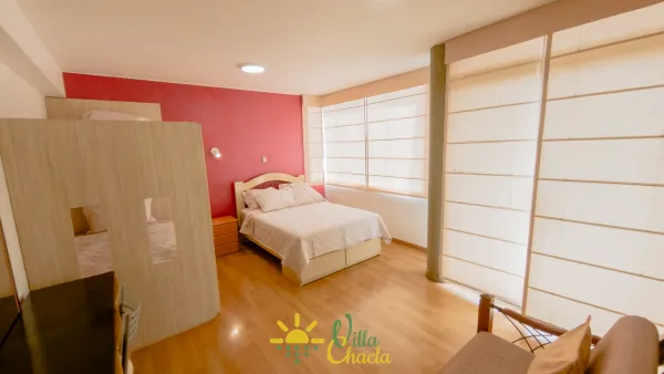 Habitación 4. Espacio elegante y lleno de energía con un vibrante muro de acento color dorado. Disfrute de una cómoda cama queen, amplio espacio de almacenamiento en el armario abierto y un práctico tocador/escritorio. Ideal para parejas que buscan un refugio acogedor con baño privado y smart tv.